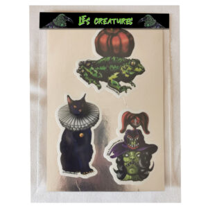 Pack de trois stickers vinyles brillants sur le thème d’Halloween : une grenouille aux multiples yeux portant une citrouille, un chat noir borgne à collerette blanche et une tête réduite de sorcière au teint vert. Illustrations originales Visual for All®.