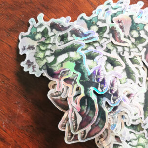 Sticker holographique représentant un hippocampe fantastique fusionné avec une fleur d’arum dans des tons pastel rose et violet.
