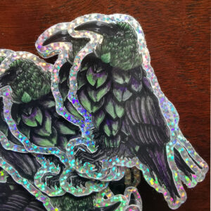 Sticker holographique pailleté représentant une créature hybride entre un corbeau noir et un artichaut vert sur fond clair.