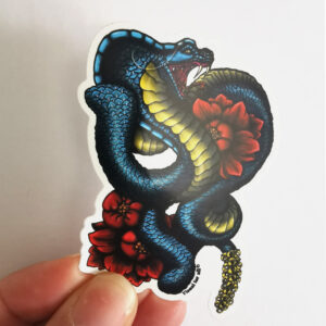 Sticker vinyle mat représentant un serpent bleu acier entouré de pivoines rouges et orangées dans un style néo-trad fantastique sur fond blanc.